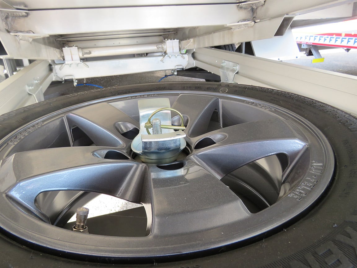 Een reservewiel met houder past onder de laadvloer.